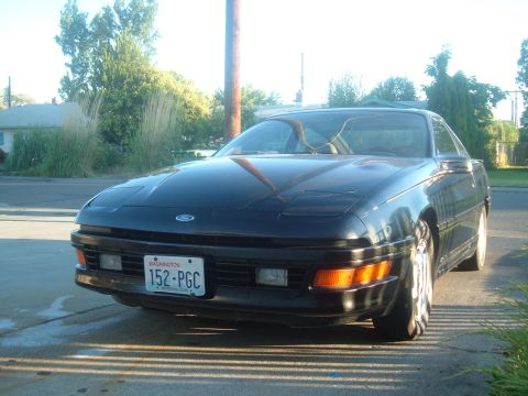 1991 Ford Probe - A dark-colored Ford Probe is parked in front of a residential area on a sunny day.