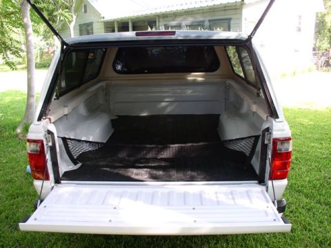 2004 Ford Ranger - The rear of a white 2004 Ford Ranger pickup truck is shown with the tailgate and cap doors open, revealing the truck bed.