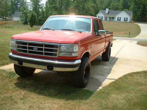 1995 Ford F-150 - Red Ford F-150 extended-cab pickup photographed from the front driver's-side corner on a concrete driveway, with a chrome front bumper, For…