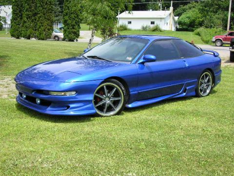 1994 Ford Probe - A blue 1994 Ford Probe GT is parked on a grassy lawn, its sporty design and custom modifications.