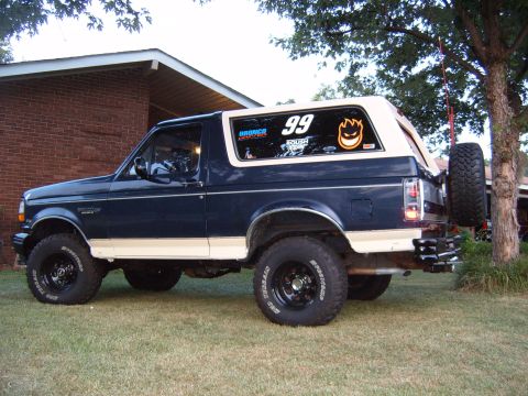 1993 Ford Bronco - 1993 Ford Bronco, rear view, parked on lawn with a spare tire on the back.