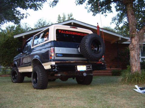 1993 Ford Bronco - This lifted Ford Bronco has a spare tire mounted on the rear and a website sticker on the back window.