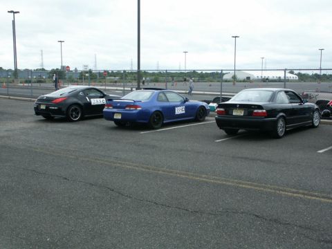 2001 Mercury Grand Marquis - Three cars are parked in a lot, two of them have racing numbers on their doors.