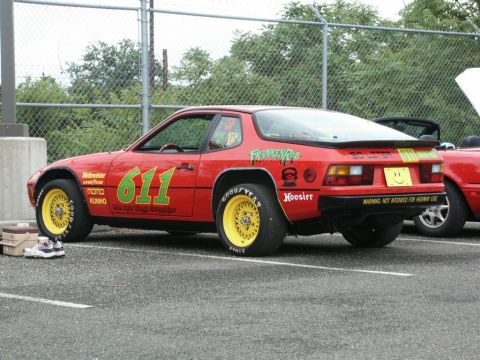 2001 Mercury Grand Marquis - A red race car with custom decals and yellow wheels is parked next to another vehicle.