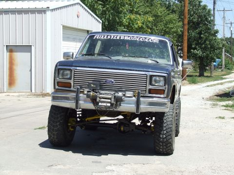 1986 Ford Bronco - This modified Ford Bronco features a lifted suspension and off-road tires, with a prominent winch mounted on the front.