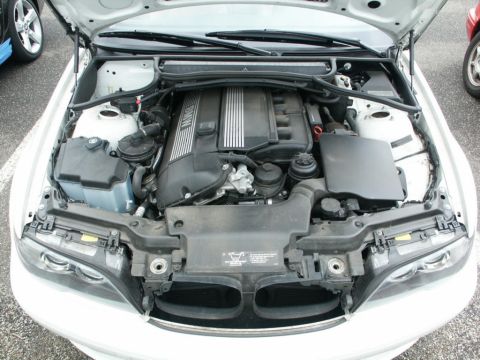 2001 Mercury Grand Marquis - The engine bay of a white car is open, showing a BMW engine. Other vehicles are visible in the background.