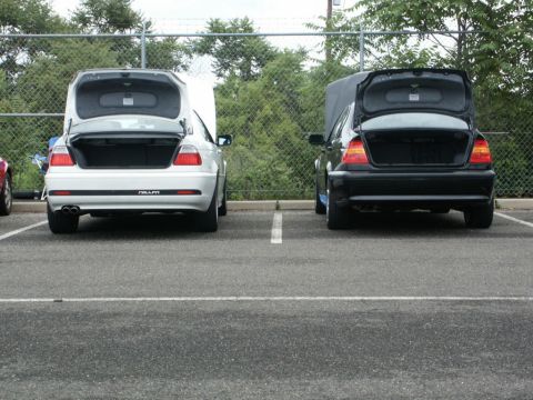 2001 Mercury Grand Marquis - Two sedans are parked in a lot with their trunks open, showing their rear ends.