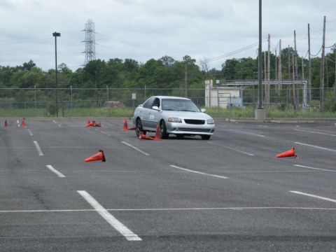 2001 Mercury Grand Marquis - A silver sedan is shown navigating a course marked by orange traffic cones in an asphalt lot.