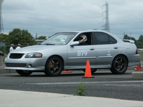 2001 Mercury Grand Marquis - Silver sedan on a track, marked with racing number 879 and driver in helmet.