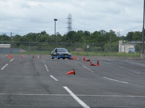 2001 Mercury Grand Marquis - BMW E36 sedan navigates an autocross course with orange cones set up on the asphalt.