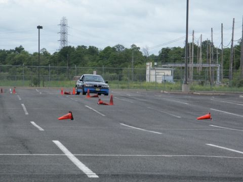 2001 Mercury Grand Marquis - A blue BMW sedan maneuvers through an obstacle course marked by orange traffic cones in an asphalt lot.