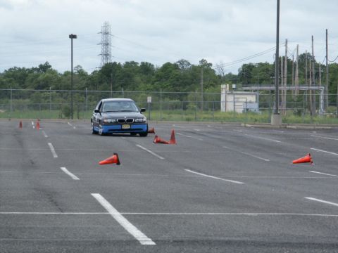 2001 Mercury Grand Marquis - A black BMW sedan with blue accents drives through an obstacle course marked by orange cones in an asphalt lot.