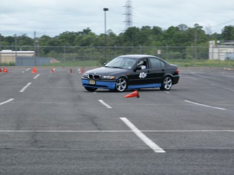 2001 Mercury Grand Marquis - A black BMW sedan with blue accents navigates a course marked by orange cones on an overcast day.