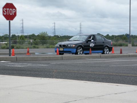 2001 Mercury Grand Marquis - A black BMW 3 Series sedan participates in an event on a track, marked with cones and a stop sign.