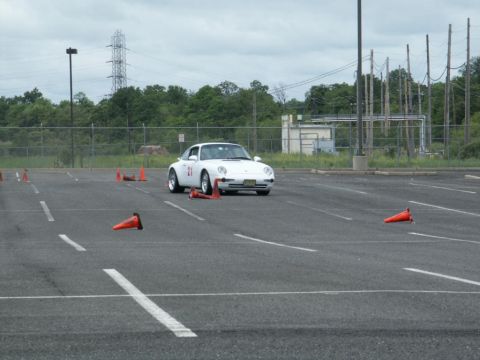 2001 Mercury Grand Marquis - A white sports car with the number 21 on its door drives through a parking lot marked with orange cones.