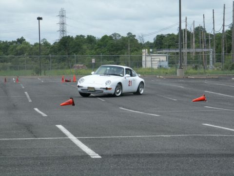 2001 Mercury Grand Marquis - Porsche 911 navigating a slalom course marked by orange cones on a cloudy day.