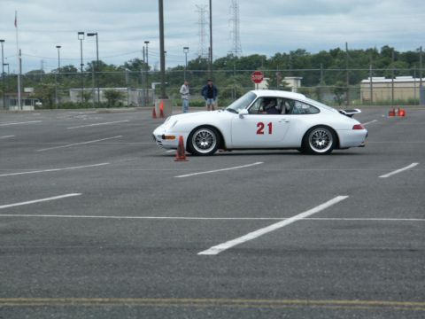 2001 Mercury Grand Marquis - A white Porsche 911 with racing number 21 navigates a course marked by traffic cones on a cloudy day.