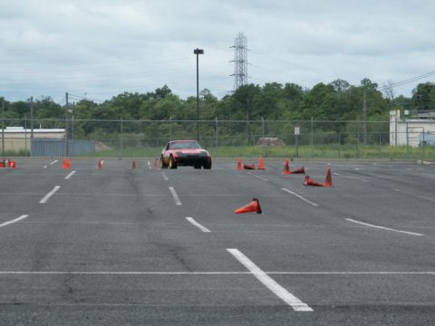 2001 Mercury Grand Marquis - A red sports car navigates a course marked by orange traffic cones on an overcast day.