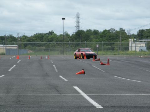 2001 Mercury Grand Marquis - A red sports car navigates a course marked by orange cones in an asphalt lot.