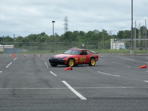 2001 Mercury Grand Marquis - A red sports coupe with racing decals and yellow wheels is seen on a paved lot with orange cones.