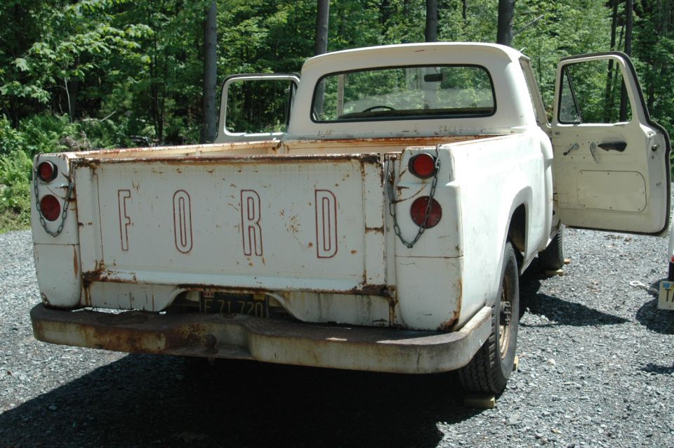 Rear view of a white 1963 Ford F-250 pickup truck with doors open