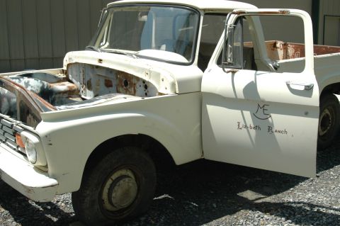 1963 Ford F-250 - This weathered pickup truck, with its hood removed, displays a ranch logo and name on the open driver's door.