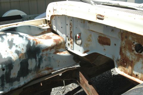 1963 Ford F-250 - Close-up of a heavily rusted truck frame and fender well, showing primer and exposed metal.