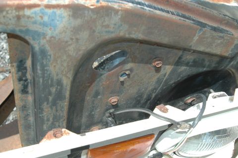 1963 Ford F-250 - Close-up of a heavily rusted vehicle component, showing bolts and electrical wiring.