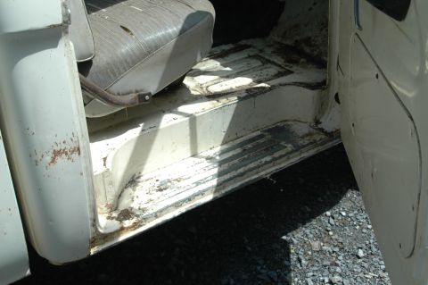 1963 Ford F-250 - The interior of a white truck cab, a worn driver's seat and floor, suggests a vehicle in need of restoration.