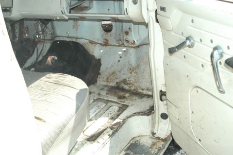 1963 Ford F-250 - The interior of a truck cab shows significant rust and wear on the floor and seat.