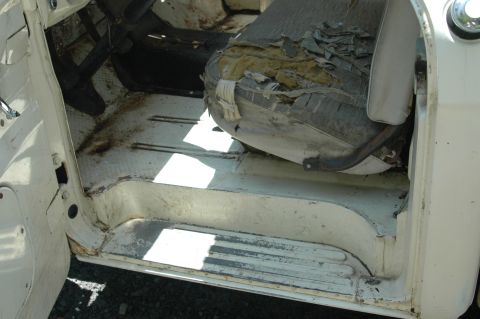 1963 Ford F-250 - Interior view of a 1963 Ford F-250 with a damaged seat and visible floor rust.