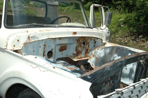1963 Ford F-250 - The front end of a white truck is shown with the hood open, revealing the engine compartment and part of the cab.