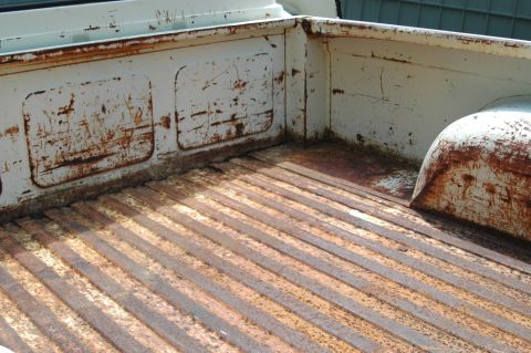 1963 Ford F-250 - The ribbed metal floor and white painted sides of a truck bed show significant rust and wear.
