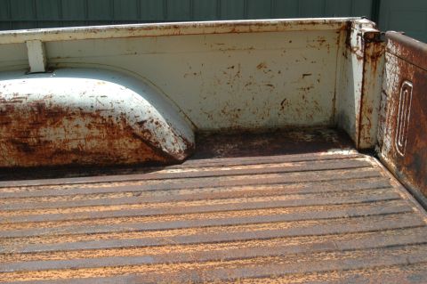 1963 Ford F-250 - The heavily rusted bed of a pickup truck shows significant wear and tear.