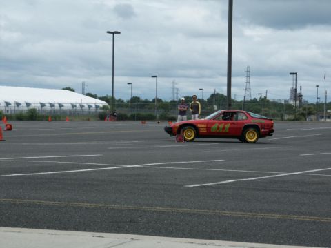 2001 Mercury Grand Marquis - A red sports coupe with racing numbers and yellow wheels sits in a parking lot, possibly at a track event.