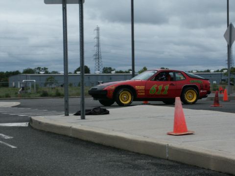 2001 Mercury Grand Marquis - A red race car with yellow wheels and racing decals sits on a paved surface next to traffic cones.