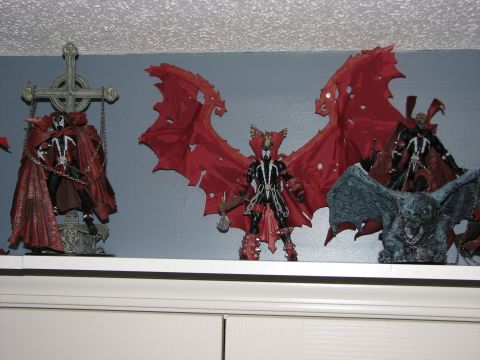 1991 Ford Bronco - A collection of Spawn action figures and a gargoyle statue are displayed on a shelf, with a SuperMotors logo visible at the bottom.