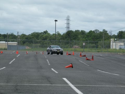 2001 Mercury Grand Marquis - A gray Ford Mustang navigates a course marked by orange cones in an asphalt lot.