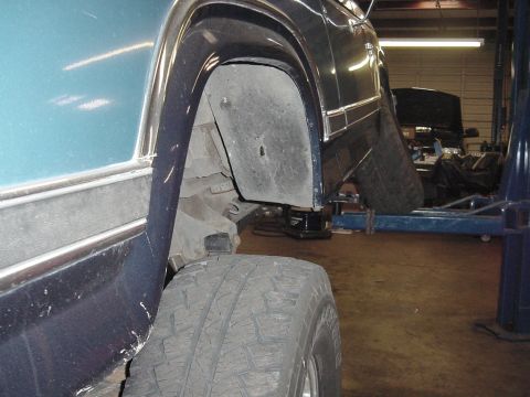 1984 Ford Bronco - Close-up of the rear wheel well and tire of a 1984 Ford Bronco, elevated on a lift.