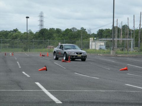 2001 Mercury Grand Marquis - A silver Ford Mustang navigates a cone course in an open lot under a cloudy sky.