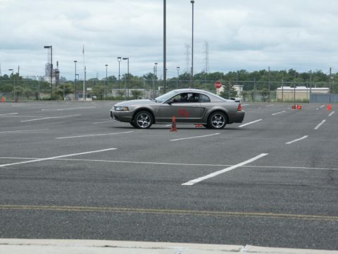 2001 Mercury Grand Marquis - Silver coupe with red racing numbers navigates a course marked by cones in a parking lot.
