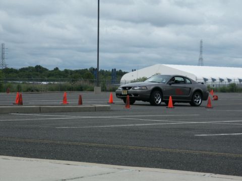 2001 Mercury Grand Marquis - Gray Ford Mustang navigates a course marked by orange cones on a cloudy day.
