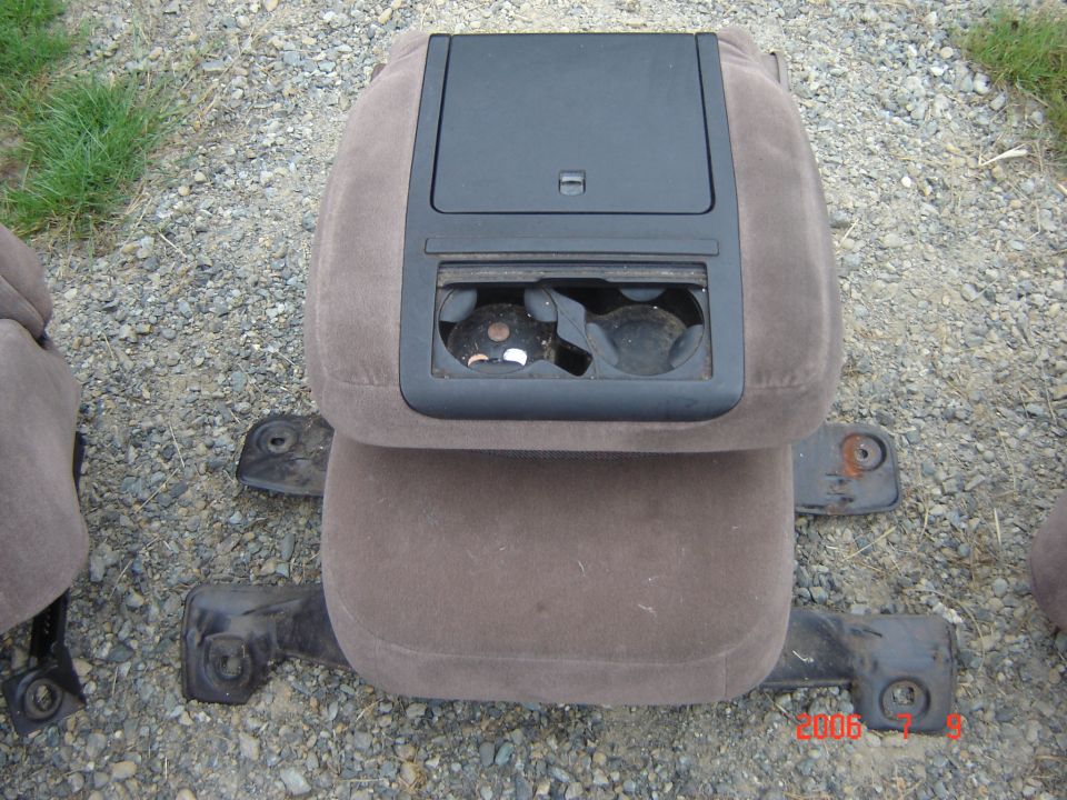 Removed brown cloth center console with cup holders on gravel
