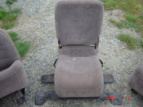 1993 Ford Bronco - Disassembled car seats, including a center jump seat, are shown on a gravel surface.