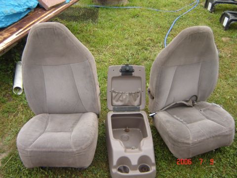1993 Ford Bronco - Vehicle interior parts, including two seats and a center console, are laid out on the grass.