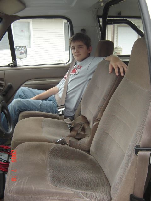 1993 Ford Bronco - A young boy sits in the passenger seat of a truck, showing the interior and a center jumpseat.