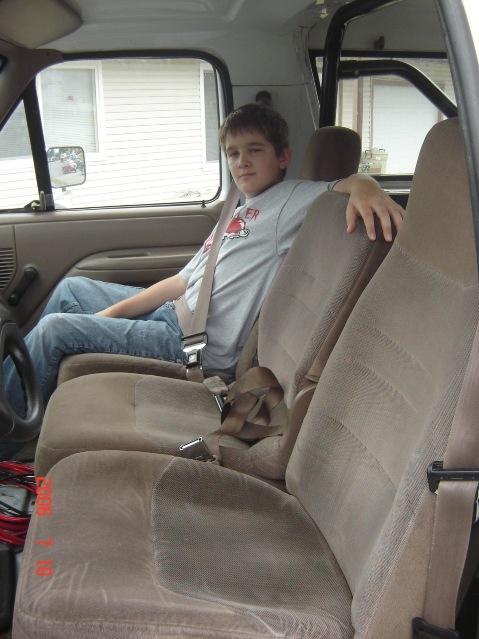 Young man seated inside a truck with tan cloth bench seats