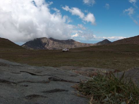1978 Ford Bronco - A white pickup truck travels through a vast, open landscape with dramatic clouds and mountains.