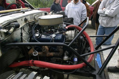 2003 Jeep TJ - Modified engine bay with prominent red hoses and a large air filter. A blue sticker with text is visible on the frame.