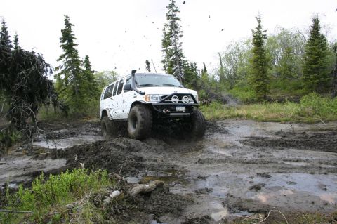 2003 Jeep TJ - White SUV navigates a challenging muddy off-road course.